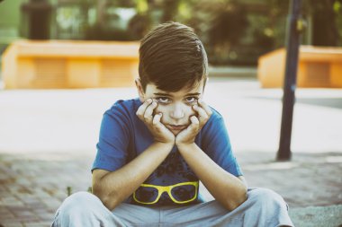 sevimli üzgün çocuk parkta güneşli bir günde surat asmayı.