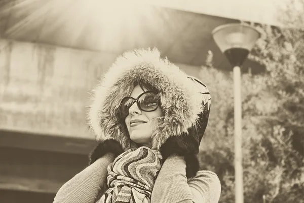 Mujer joven en capucha caliente en la cabeza al aire libre disfrutando de la luz del sol en día soleado . — Foto de Stock