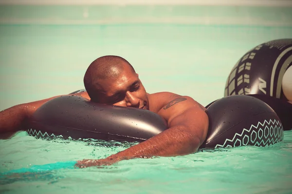 Hombre divirtiéndose y relajándose en el anillo de goma en la piscina —  Fotos de Stock