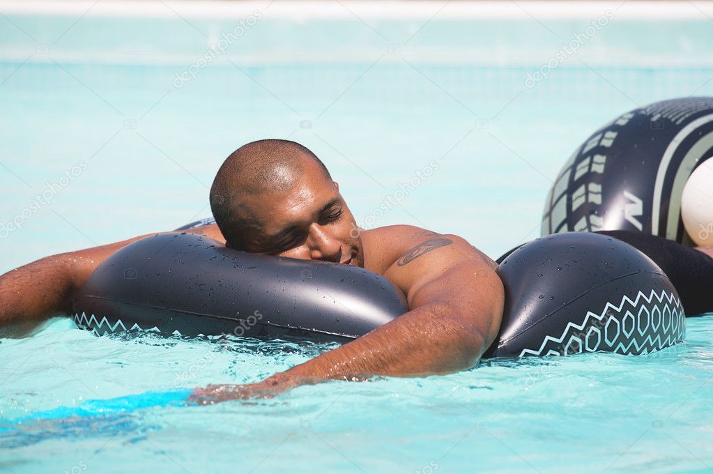 Man having fun and relaxing on the rubber ring in the swimming pool