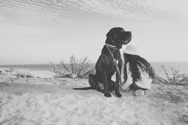 Dívka s pes sedí na pláži — Stock fotografie