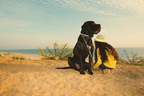 Κορίτσι με ένα σκυλί να κάθεται στην παραλία — Φωτογραφία Αρχείου