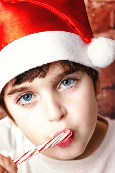 Positive little boy in santa's hat holding candy canes ready for festive christmas time Royalty Free Stock Images