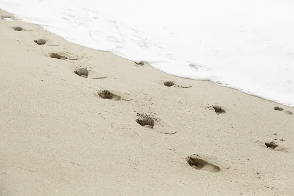 Lábnyomok a homokos tengerparton — Stock Fotó