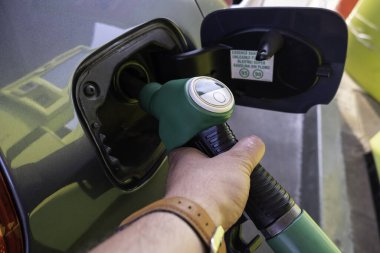 Arabasına benzin koyan genç adamın ayrıntıları.