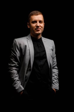 Siyah arka planda gri ceketli genç adam.