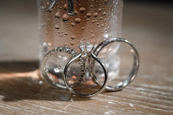 Trauringe Neben Einer Flasche Parfüm Mit Tropfen Und Spritzern — Stockfoto