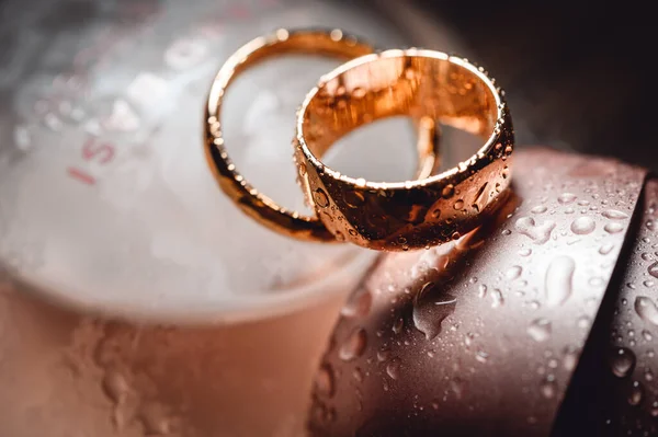 Trauringe Neben Einer Flasche Parfüm Mit Tropfen Und Spritzern — Stockfoto