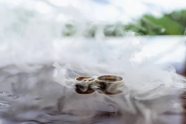 Wedding rings in water with smoke