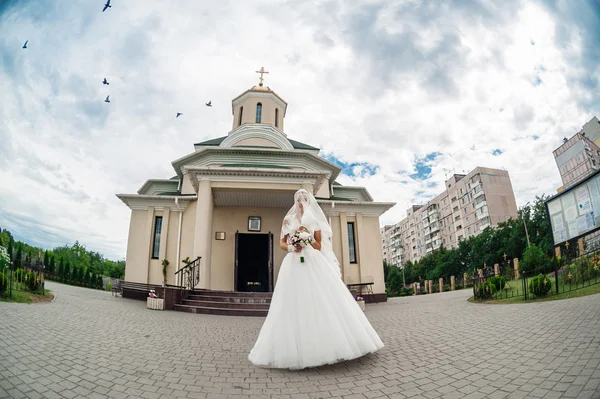 Nevěsta s květinami nedaleko kostela — Stock fotografie