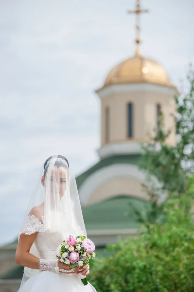 Noiva com flores perto da igreja — Fotografia de Stock