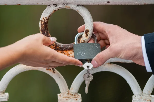 Bride and groom holding love lock — Stock Photo, Image