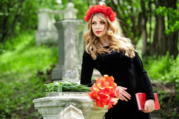 Chica con una corona roja y flores — Foto de Stock