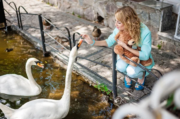 Mujer rubia alimenta cisnes blancos —  Fotos de Stock