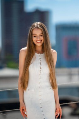 Beyaz elbiseli, gülümseyen beyaz kadın, rahat etkili poz veren, uzun heteroseksüel kadın.