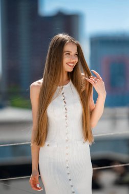 Beyaz elbiseli, gülümseyen beyaz kadın, rahat etkili poz veren, uzun heteroseksüel kadın.