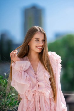 Gülümseyen Pembe Giysili Genç Kadın, Uzun Saçlı, Hafif Güneş Işıklı Dokunaklı Saçlı, Doğal Makyajlı, Bulanık