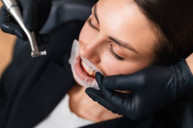 Modern Diş Kliniği 'nde Diş beyazlatma prosedüründen geçen beyaz kadın siyah diş hekimi.