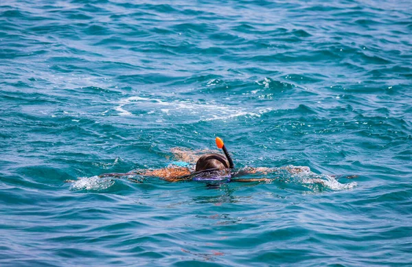 Young guy swims in azure water wearing a mask with a snorkel for breathing — Stock Photo, Image