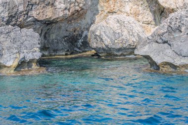 Kıbrıs 'ta masmavi suyla çevrili taştan bir uçurumla çevrili küçük bir durgun su