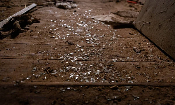 Apró üvegszilánkok egy koszos barna fapadlón — Stock Fotó