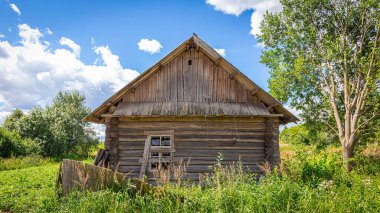 Güneşli bir günde yıkılmış çitli bir köyde çökmüş bir ev. 