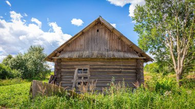 Güneşli bir günde yıkılmış çitli bir köyde çökmüş bir ev. 