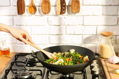 Kadın gaz tabağında vejetaryen yemeği pişiriyor.