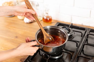 Kadın mutfakta gaz tabağında çorba pişiriyor.