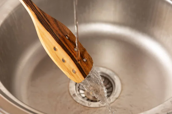 Suyun altında bir spatula yıkıyorum.