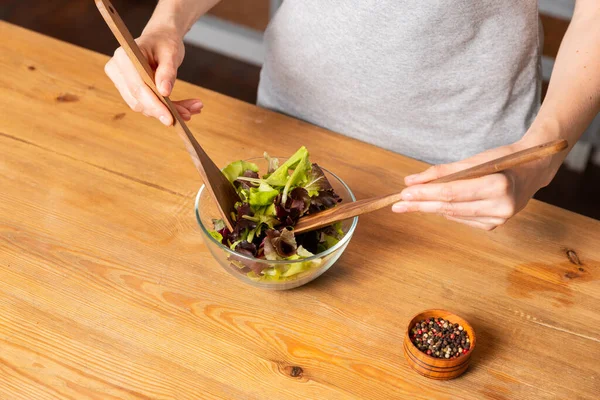 Kadınlar ahşap masada salata pişirir.
