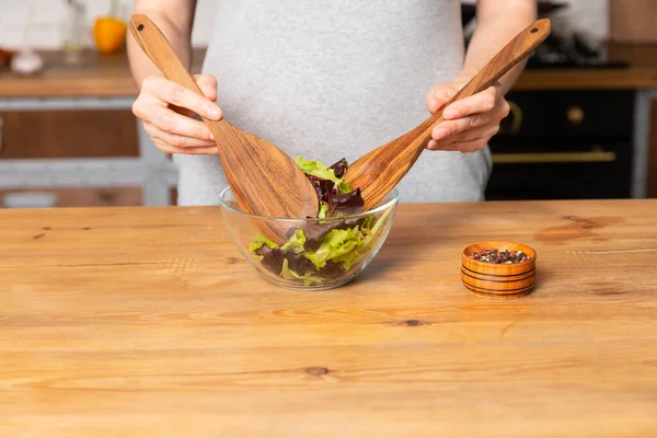 Kadınlar ahşap masada salata pişirir.