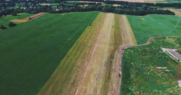 Vliegen op een Drone boven het veld waar de trekker werkt — Stockvideo