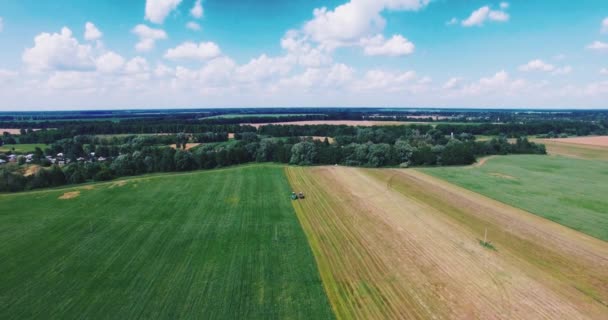 Vliegen op een Drone boven het veld waar de trekker werkt — Stockvideo