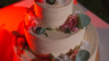 Masadaki düğün pastasının romantik çiçek tasarımı