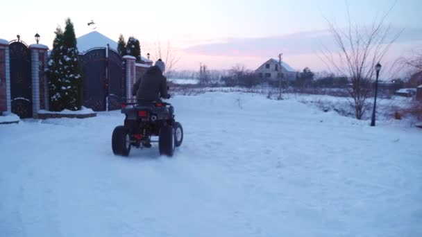 Killen snurrar på en fyrhjuling i snön. — Stockvideo