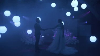 Gelin ve damat sahnede ilk dansı yaparlar, lazer projeksiyonları ve aşağı yukarı hareket eden bir sürü beyaz topların etrafında.