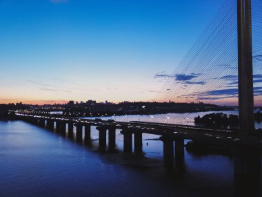 Gün batımına karşı güzel bir köprü bulutlarla, arabalar köprüde.