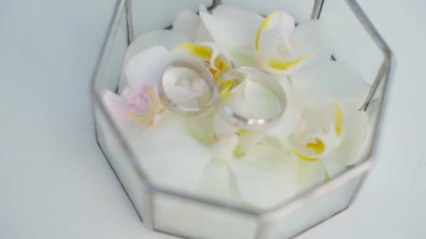 Свадебные принадлежности на туалетном столике: свадебный букет белых пионов, обручальные кольца в стеклянной коробке, золотые туфли. подготовка к свадьбе — стоковое видео