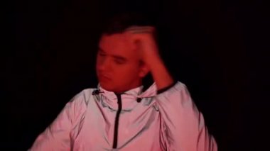 Diskoda dans eden, siyah arka planda dans eden, yansıtıcı ceketli, disko ışığı olan bir adam.