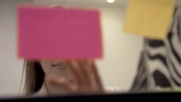 Gerente feminina toma notas adesivas com sorriso de uma placa de vidro, close-up — Vídeo de Stock