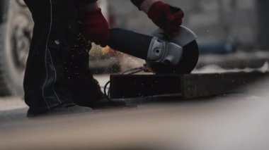 Fabrikada kesme tekeriyle metal kesen bir adam var.