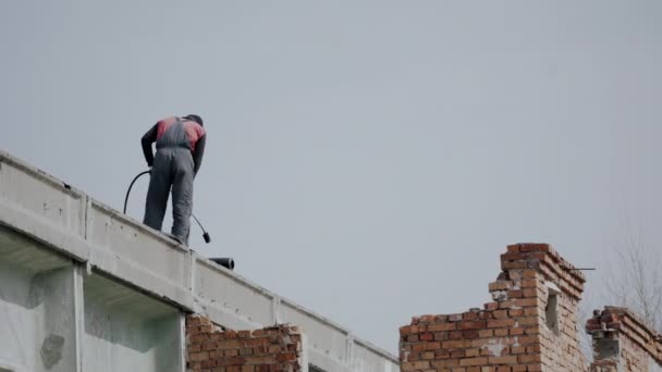 L'uomo sul tetto posare materiale di copertura nero sul tetto piatto bianco. — Video Stock