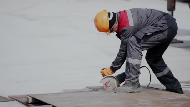 Werknemer draagt masker en snijdt metaal met de hand schijf slijper slijpzaag — Stockvideo