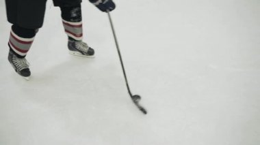 Hokey oyuncusu buz üstünde sopayla topa vuruyor, yakın plan.