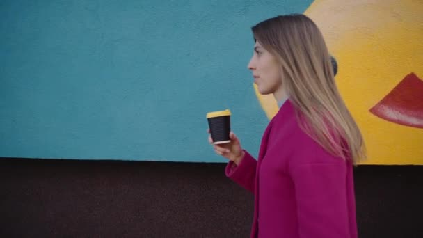 Дівчина йде по вулиці і п'є каву — стокове відео