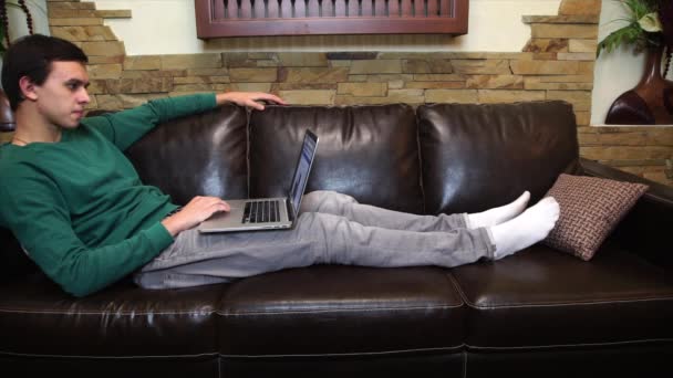 Man lying on the couch and working on the computer — Stock Video