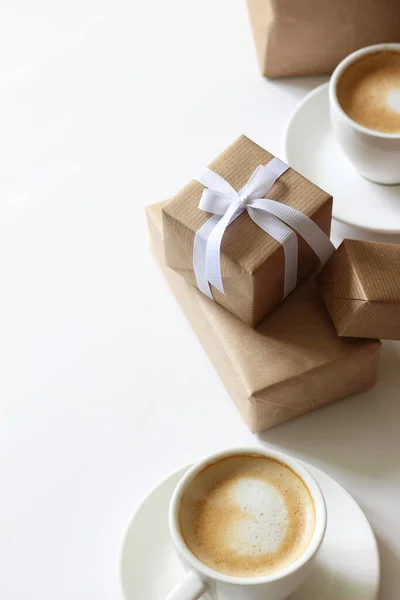 Packaging Holiday Gifts. Gift Boxes and Cups of Cappuccino Coffee on White. Holidays Background.