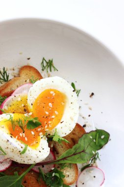 Kahvaltıda. Sıvı yumurta sarısı, susam tohumlu taze ot ve kızarmış ekmek üzerine biber..