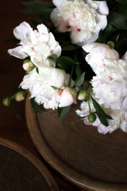 Tahta sandalyede bir buket Beyaz Şakayık. Asgari İçten Kremalı Şakayıklar. İç Dekorasyon.